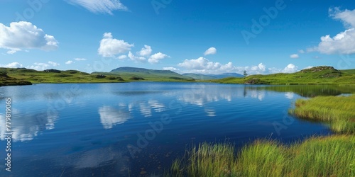 A calm lake with a few trees in the background. The sky is blue with some clouds. The water is still and clear