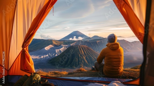 Male traveler relaxing in a tent and enjoying the view of the volcano.AI generated image