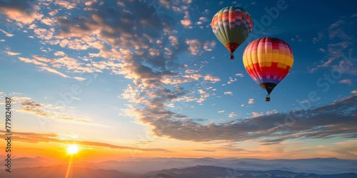 Two hot air balloons are flying in the sky above a beautiful sunset. The sky is filled with clouds, creating a serene and peaceful atmosphere. The hot air balloons are of different colors