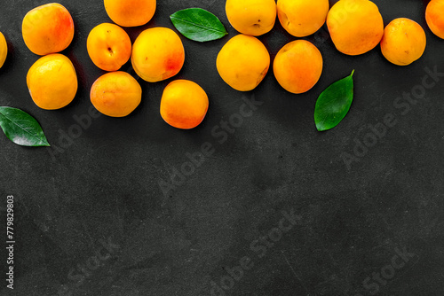 Fruit frame. Apricots and leaves on black background top view copy space