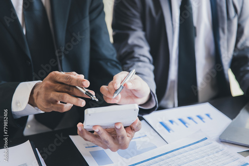 Two Businessman bsing calculator calculating data in reports and Financial data analyzing. Business team meeting and discussing project plan. Businessmen discussing together in meeting room.