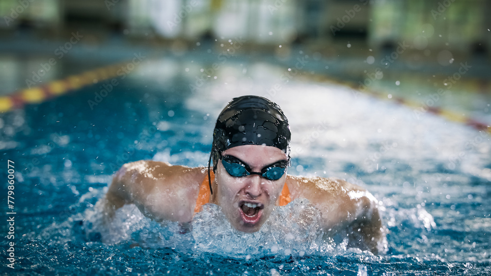 Female competitive swimmer moving through the water performing the butterfly stroke during swimming training, front view.