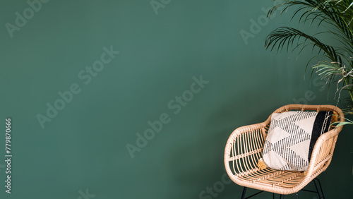 Comfortable rattan armchair with soft cushion on green wall background © brizmaker