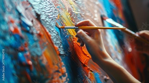 An anonymous female artist paints colorful paint on canvas while working in a creative studio.