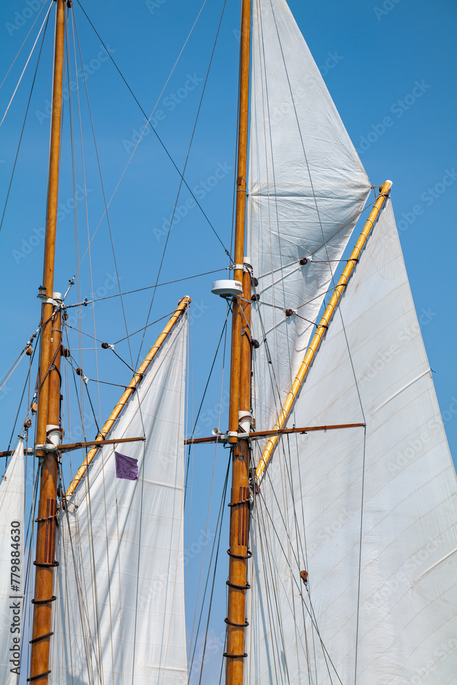 White Dacron sails on a classic wooden sail boat with wooden masts. White Dacron sails on a classic wooden sail boat with wooden masts.