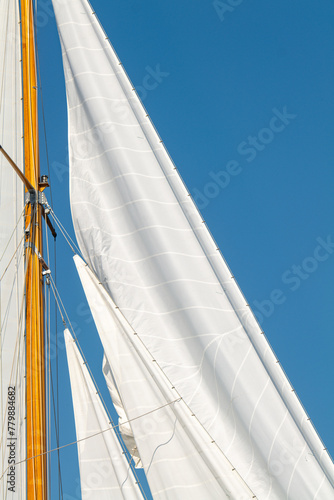 White Dacron sails on a classic wooden sail boat with wooden masts.