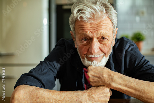Concerned elderly man sitting at kitchen table photo