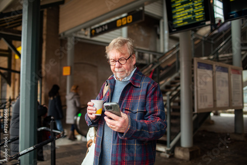 Senior man at the train station using smartphone photo
