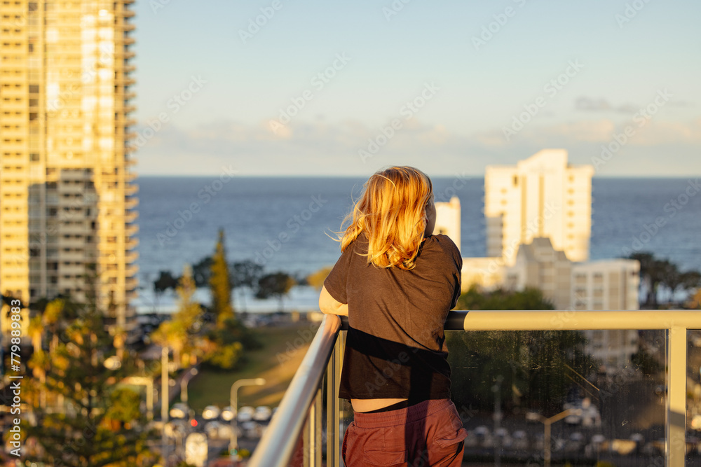 Pre-teen boy standing on balcony of high rise building on the Gold Coast with view of city Pre-teen boy standing on balcony of high rise building on the Gold Coast with view of city