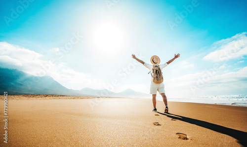 Happy traveler with hands up standing at the beach - Delightful man enjoying success and freedom outdoors - Wanderlust, wellbeing, travel and summertime holidays concept