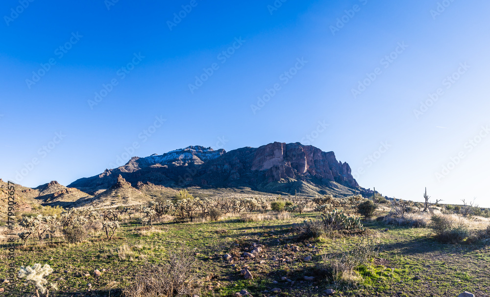 Daytime panorama photo of the Superstition Mountains in Arizona with a light dusting of snow and clear blue sky. Daytime panorama photo of the Superstition Mountains in Arizona with a light dusting of snow and clear blue sky.