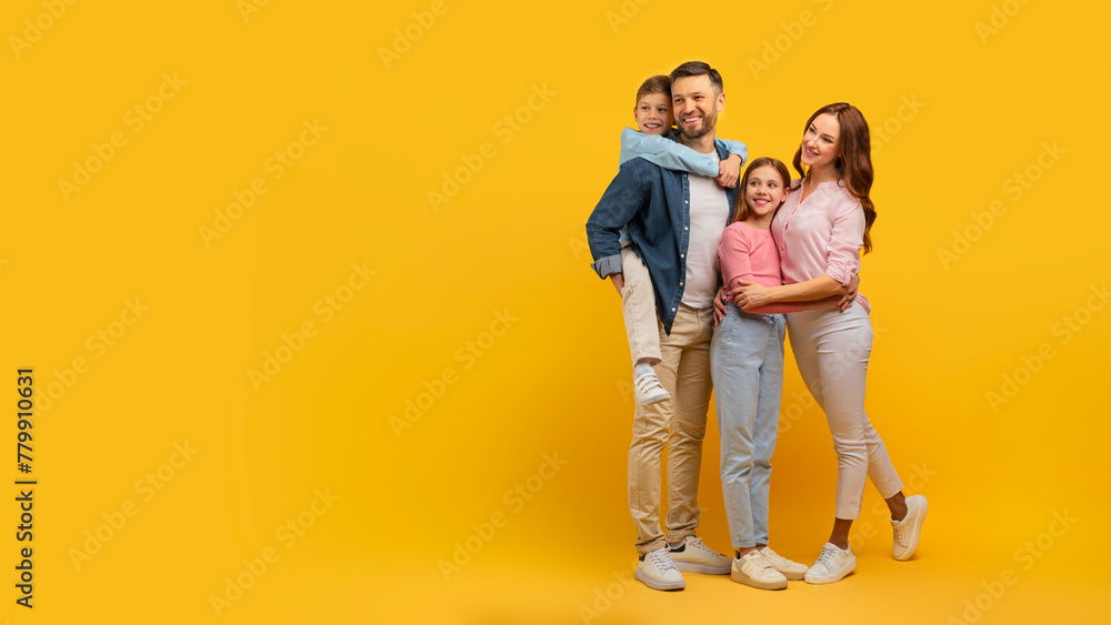 Family embraced and smiling on yellow background - obrazy, fototapety, plakaty 