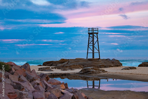Old wooden lifeguard, shark lookout tower on Redhead Beach with reflection