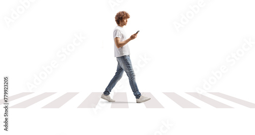 Young man holding a smartphone and crossing a street at pedestrian zebra
