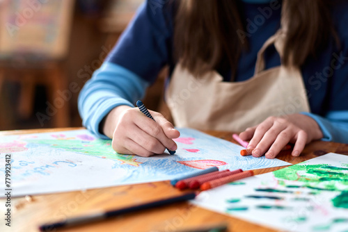 Close up of unrecognizable teen girl drawing picture with crayons sitting at table in art studio copy space