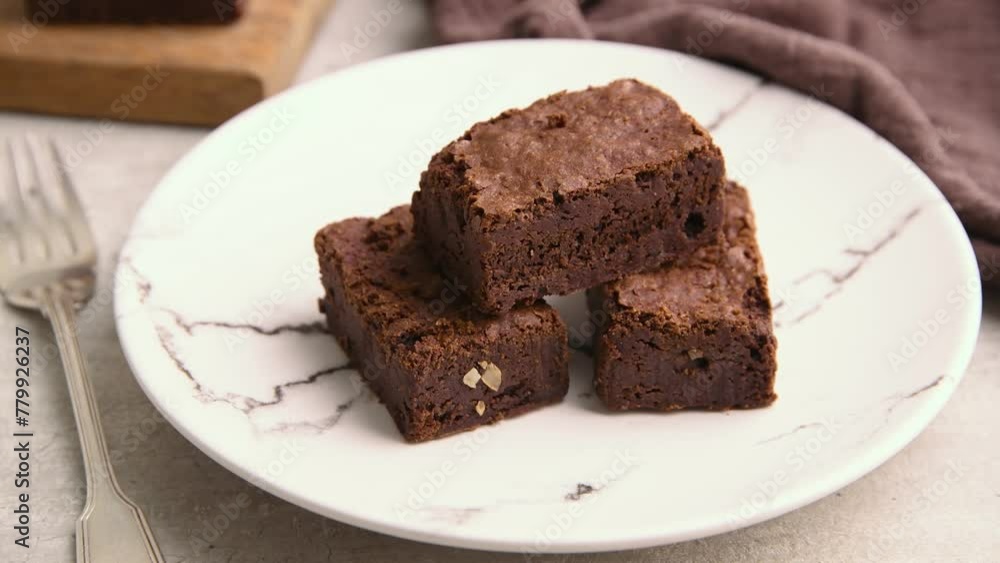 Putting a piece of brownie over other pieces on a white plate Putting a piece of brownie over other pieces on a white plate