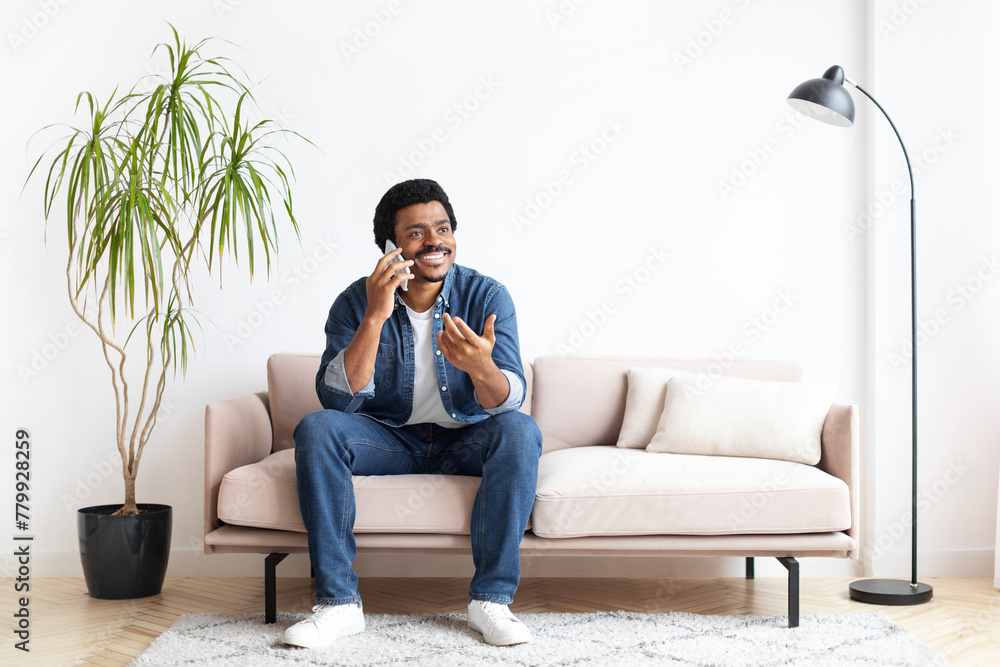 Black Man Sitting On Couch And Talking On Cell Phone