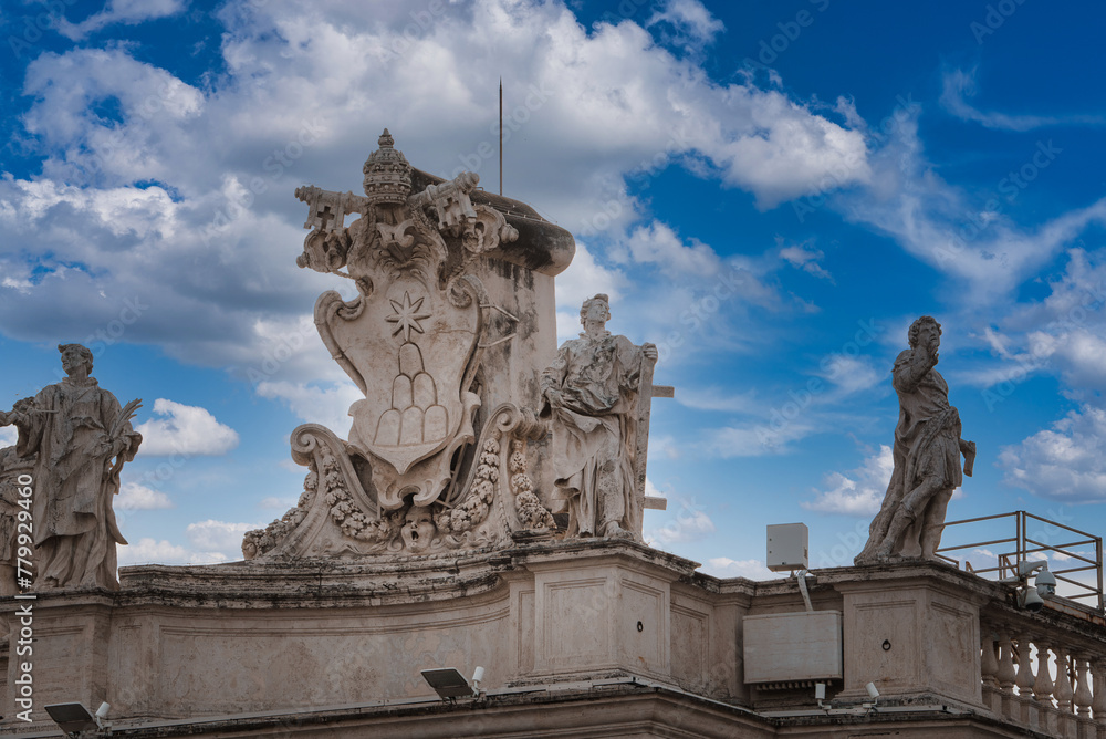 Ornate architectural details in Vatican City rooftop statues, coat of arms, religious figures in contemplative pose. Dramatic sky with historical significance and modern elements.