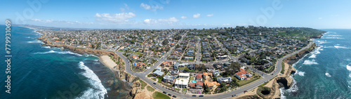 Aerial panorama of Sunset Beach in San Diego with ragged California ocean coastline, crushing waves, luxury single family homes and residences with pools