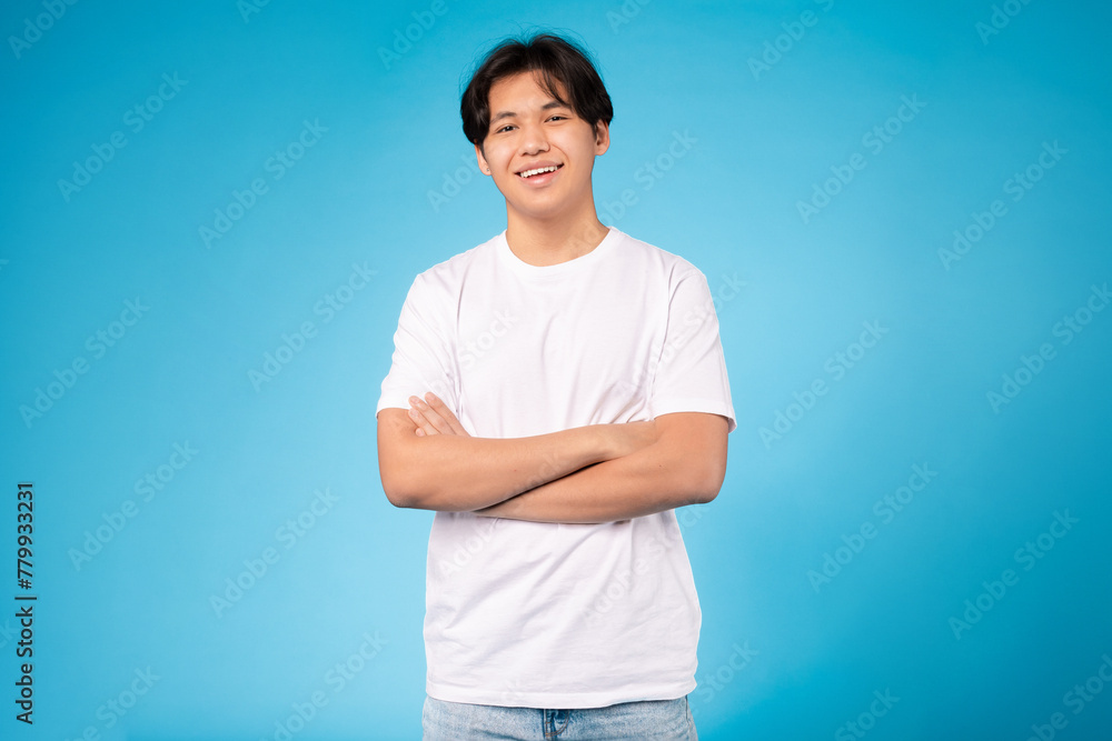 Cheerful young guy with arms crossed, blue background Cheerful young guy with arms crossed, blue background