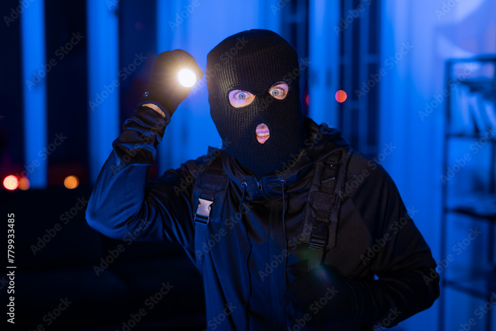 Intruder with a flashlight searching in blue hue Intruder with a flashlight searching in blue hue