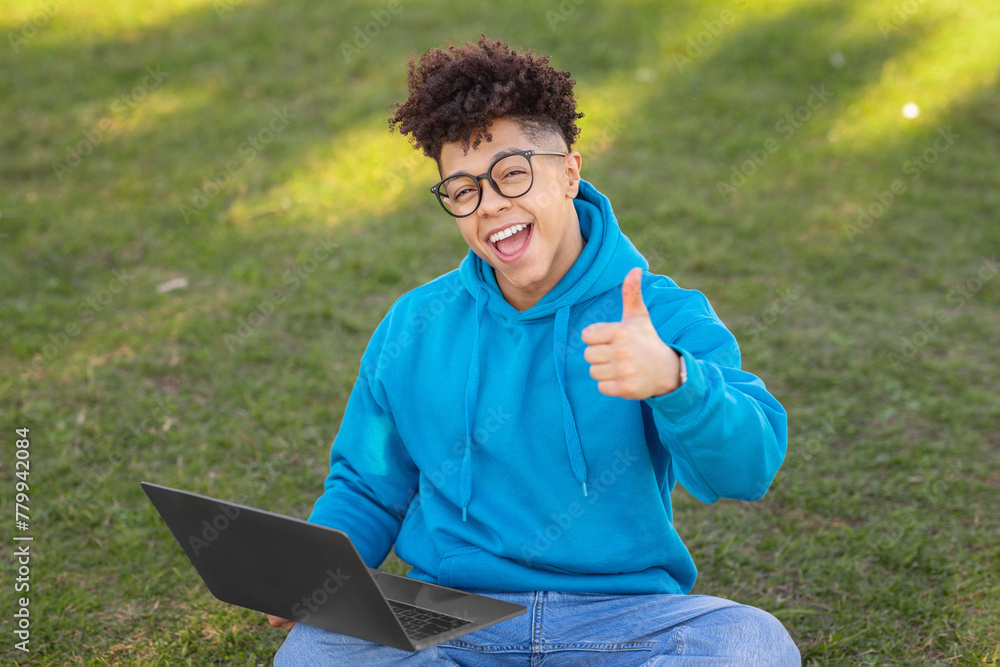 Enthusiastic student giving thumbs up, studying at park