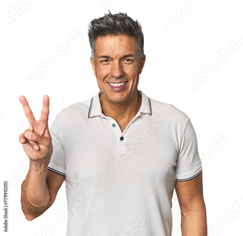 Middle-aged Latino man showing victory sign and smiling broadly.