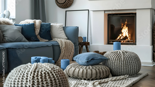 Grey sofa with blue pillows next to the fireplace and beige knit pouffes in between. a warm and inviting winter setting. Scandinavian interior design for a contemporary living room photo