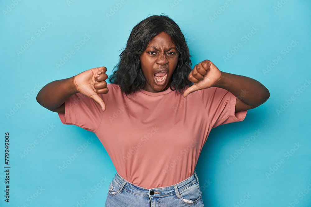 Young african american curvy woman showing thumb down and expressing dislike. Young african american curvy woman showing thumb down and expressing dislike.