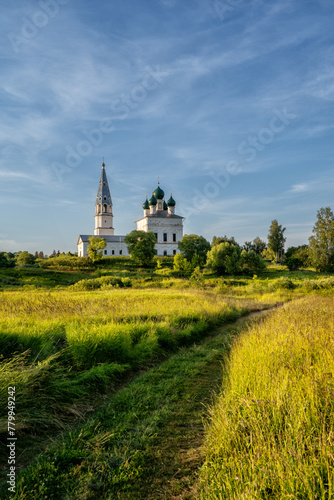 Rustic landscape, road through the field, ahead of the church in the village of Osenevo, Russia