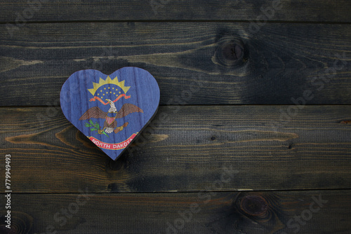 wooden heart with national flag of north dakota state on the wooden background.