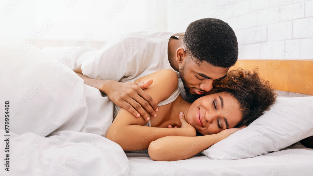 Handsome man kissing woman on cheek under in bed Handsome man kissing woman on cheek under in bed