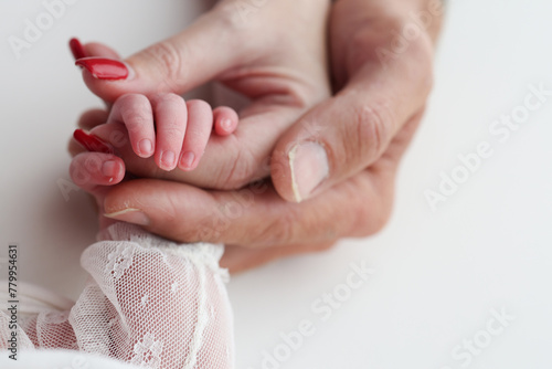 Close-up little hand of child and palm of mother and father. The newborn baby has a firm grip on the parent s finger after birth. A newborn holds on to mom s  dad s finger.