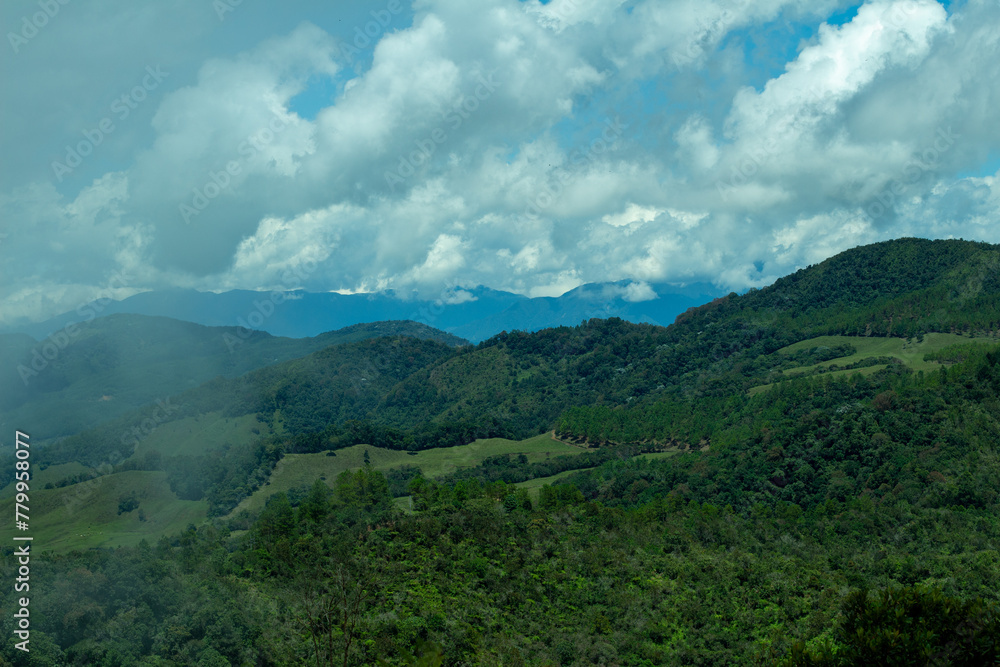 Bright panorama of the cloudy Andes Mountains from the Cerro las Nubes, Mount of the Clouds, in Jerico, Jericó, Antioquia, Colombia. Blue sky whith clouds and mist. Green lush vegetation.