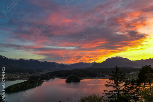 Panoramic sunset view on Lake Faak from Taborhoehe in Carinthia, Austria, Europe. Surrounded by high Austrian Alps mountains. Water surface reflecting soft sunlight. Remote alpine landscape in summer © Chris