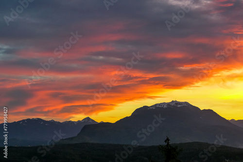 Wallpaper Mural Scenic view of snow capped mountain peak Dobratsch at sunset seen from Taborhoehe in Carinthia, Austria, Europe. Sky has vibrant orange and pink colors with clouds swirling around summit. Serenity Torontodigital.ca