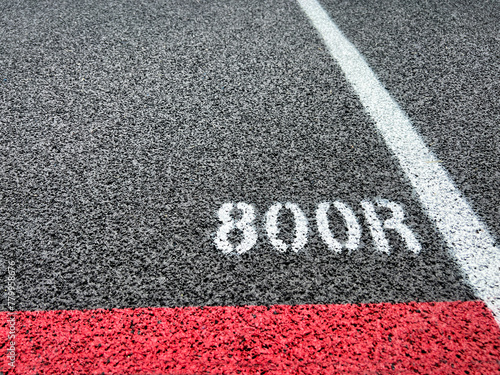 Track and Field Running Lanes. Overhead view of a rubber black running  surface with white lane lines. Focus on the 800 meter staggered start line. Rubber black surface with red start line. photo
