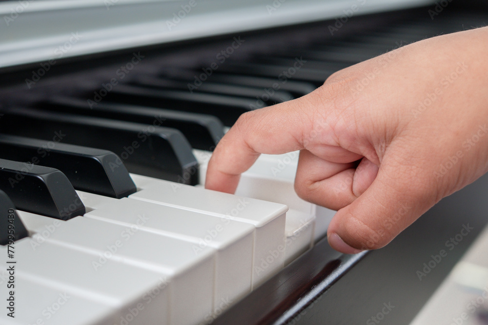 Fototapeta premium Closeup to a child hand using his one finger to press the piano key