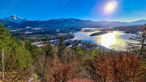 Panoramic sunset view on Lake Faak from Taborhoehe in Carinthia, Austria, Europe. Surrounded by high snow capped Austrian Alps mountains. Surface of lake is frozen. Alpine Landscape in frosty winter photo