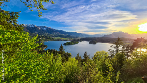 Panoramic sunset view on Lake Faak from Taborhoehe in Carinthia, Austria, Europe. Surrounded by high Austrian Alps mountains. Water surface reflecting soft sunlight. Remote alpine landscape in summer photo