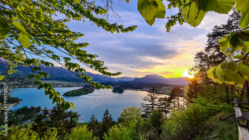 Panoramic sunset view on Lake Faak from Taborhoehe in Carinthia, Austria, Europe. Surrounded by high Austrian Alps mountains. Water surface reflecting soft sunlight. Remote alpine landscape in summer photo