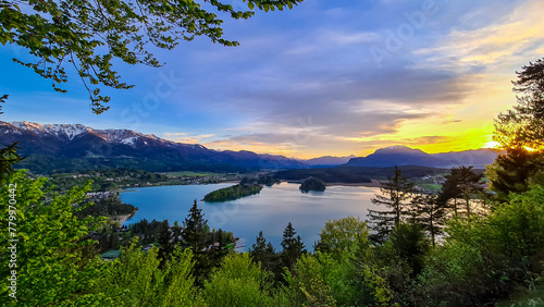 Panoramic sunset view on Lake Faak from Taborhoehe in Carinthia, Austria, Europe. Surrounded by high Austrian Alps mountains. Water surface reflecting soft sunlight. Remote alpine landscape in summer photo