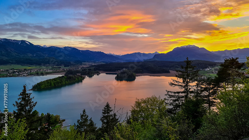 Panoramic sunset view on Lake Faak from Taborhoehe in Carinthia  Austria  Europe. Surrounded by high Austrian Alps mountains. Water surface reflecting soft sunlight. Remote alpine landscape in summer