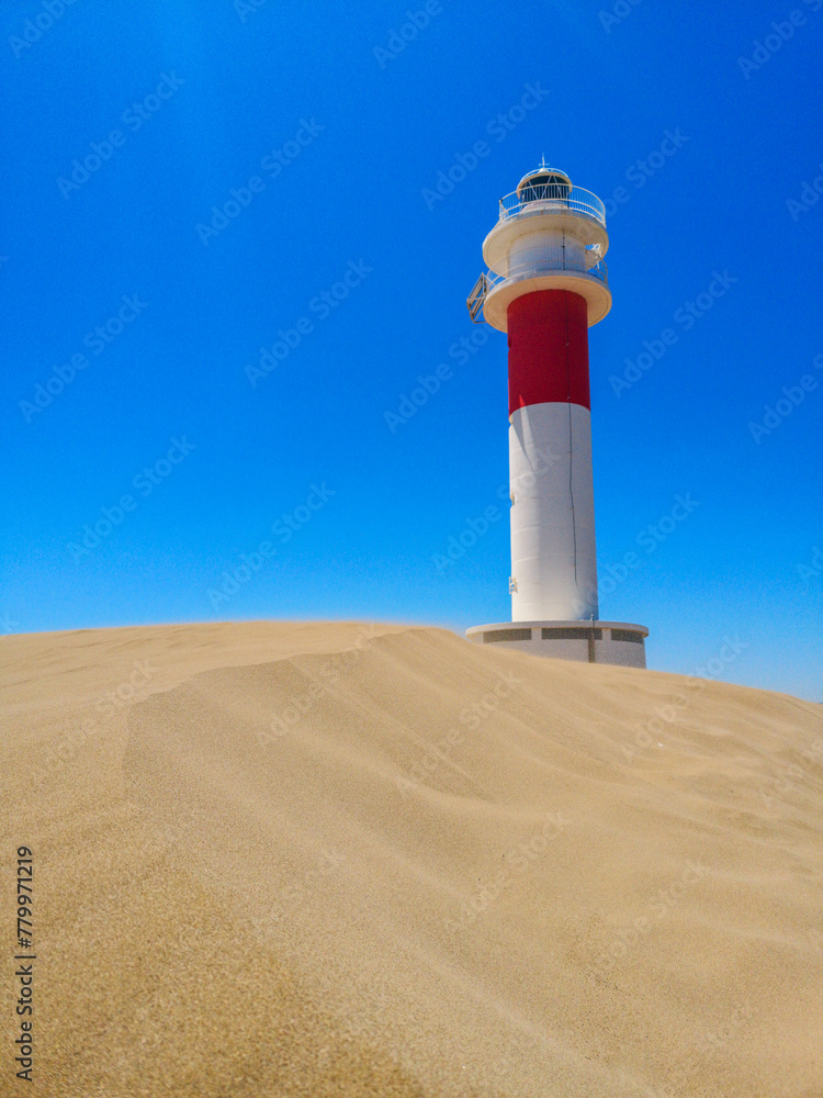 Lighthouse on the sand in the Ebro Delta with a blue sky in the background. Vertical