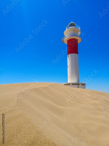 Lighthouse on the sand in the Ebro Delta with a blue sky in the background. Vertical