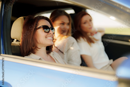 Three friends sharing a moment of joy while on a road trip as the sun sets, capturing the essence of friendship and adventure. © arthurhidden
