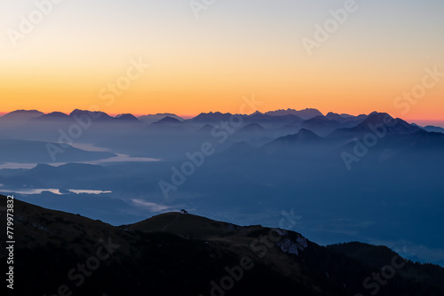 Panoramic sunrise view from Dobratsch on the Julian Alps and Karawanks in Austria, Europe. Silhouette of endless mountain ranges with orange and pink colors of sky. Jagged sharp peaks and valleys