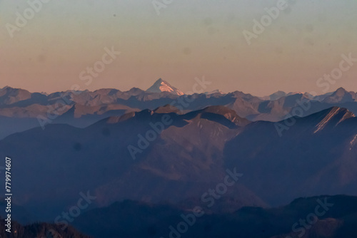 Panoramic sunrise view from summit Dobratsch on High Tauern  Hohe Tauern  in Austria  Europe. Silhouette of endless mountain ranges with orange and pink colors of sky. Jagged sharp peaks and valleys