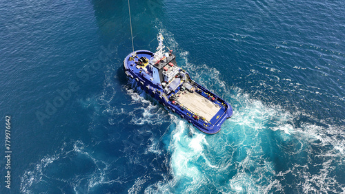 Aerial drone top down photo of industrial tug assisting boat cruising in deep blue Mediterranean sea