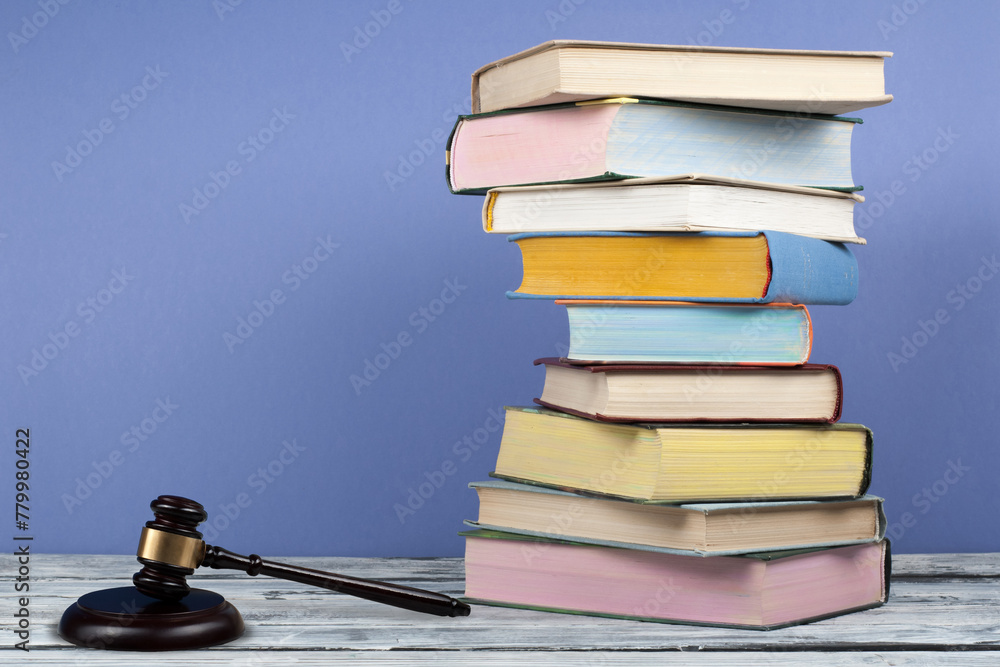 Law concept open book with wooden judges gavel on table in a courtroom or law enforcement office, blue background. Copy space for text. Law concept open book with wooden judges gavel on table in a courtroom or law enforcement office, blue background. Copy space for text.